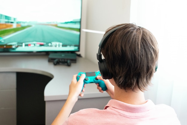 Adolescente juega un juego de computadora con auriculares y un joystick, consola de juegos.