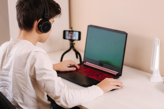 Adolescente jugando en su computadora pc en la habitación blanca