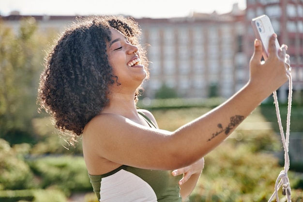 Adolescente latina com cabelo encaracolado tirando uma selfie ou videochamada enquanto ri