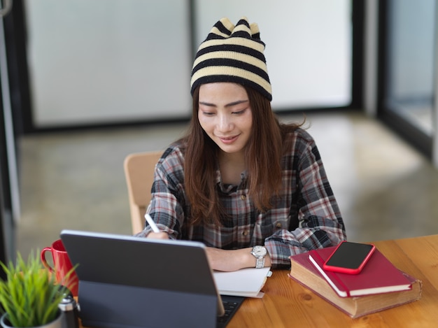 Adolescente con libro y tableta en café