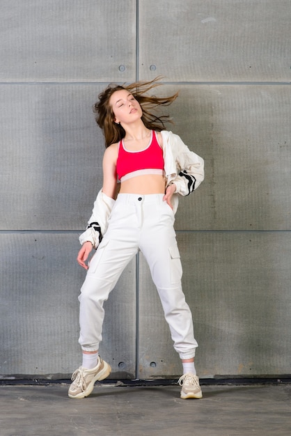 Adolescente lindo bailando hip hop en pantalones reflectantes