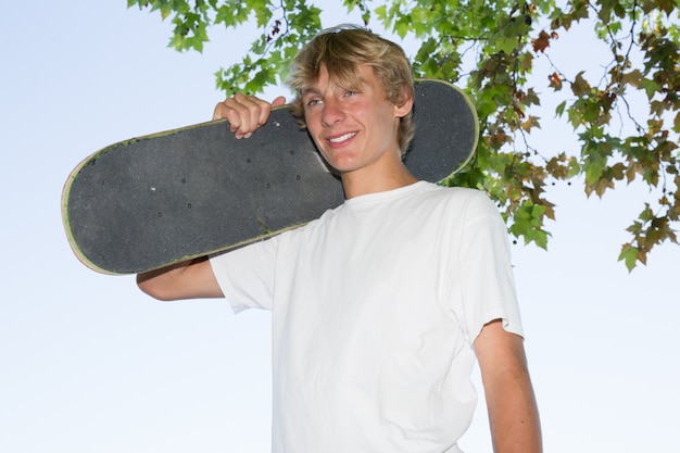 Adolescente loiro segurando um skate