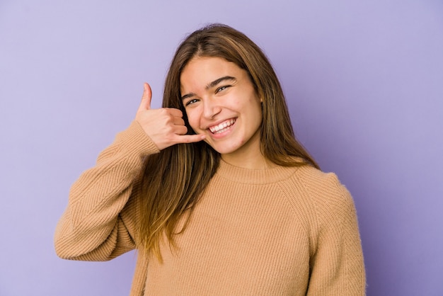 Adolescente magro de menina caucasiana em fundo roxo, mostrando um gesto de chamada de telefone móvel com os dedos.