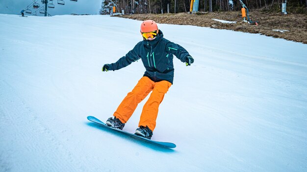 Adolescente masculino dando un giro con su tabla de snowboard en un día nublado