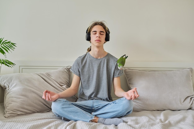 Adolescente masculino sentado en posición de loto en la cama relajante meditando