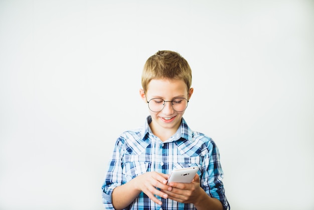 Foto adolescente menino gay de óculos, sorrindo com o smartphone.