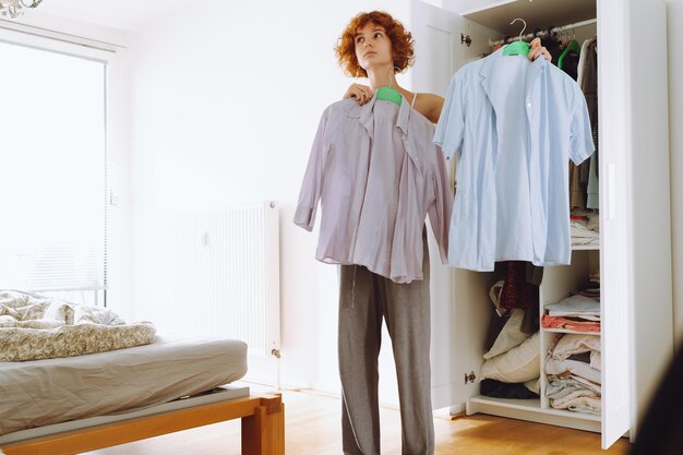 Foto una adolescente mirando la ropa en el armario.