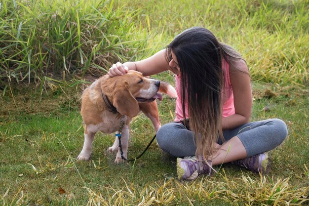 Adolescente morena con perro beagle en el parque al aire libre