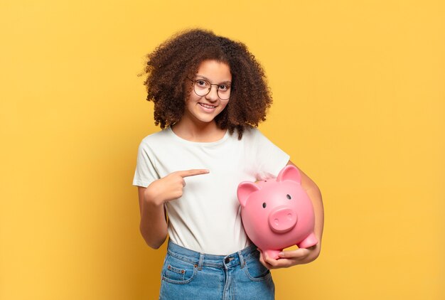 Adolescente muito afro parecendo feliz, apontando para o lado e sorrindo. conceito de economia