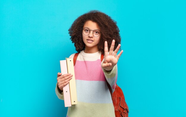 Adolescente muito afro sorrindo e parecendo amigável, mostrando o número quatro ou quarto com a mão para a frente, em contagem regressiva. conceito de estudante