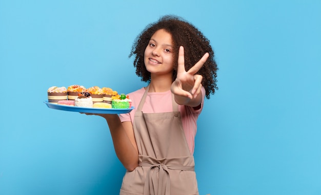 Adolescente muito afro sorrindo e parecendo feliz, despreocupado e positivo, gesticulando vitória ou paz com uma mão. conceito de padeiro humorístico