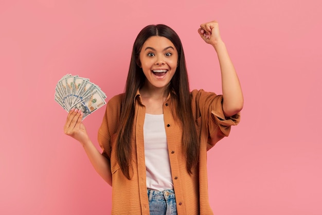 Foto adolescente muito feliz segurando leque de notas de dólar e apertando o punho