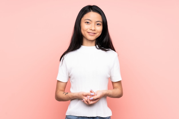 Adolescente mujer china en la pared rosa riendo