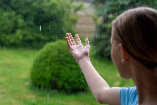 Adolescente na chuva no verão no pátio da casa