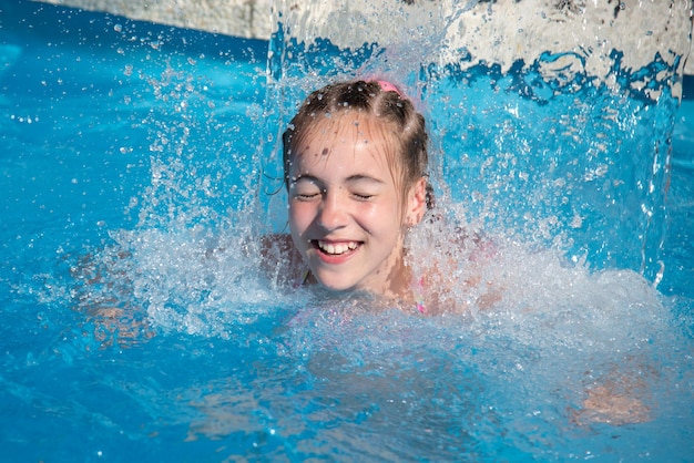 Una adolescente nada en una piscina con agua azul Tiene trenzas africanas trenzadas con cintas zizi