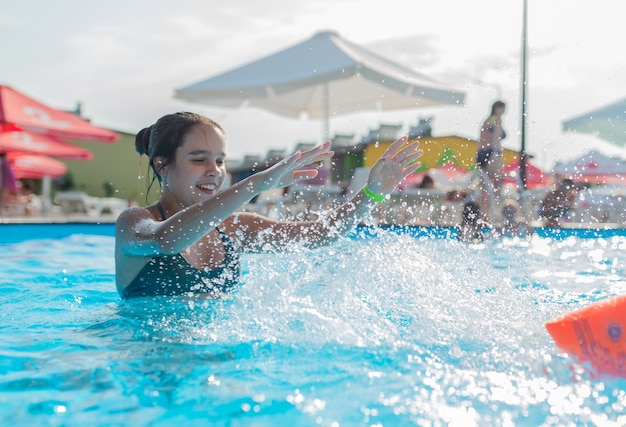 Adolescente nadando na água azul clara de uma piscina durante as férias em um país tropical quente