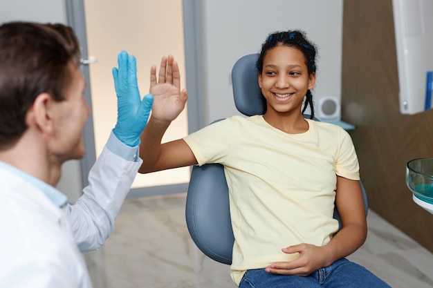 Adolescente negra fazendo highfiving dentista