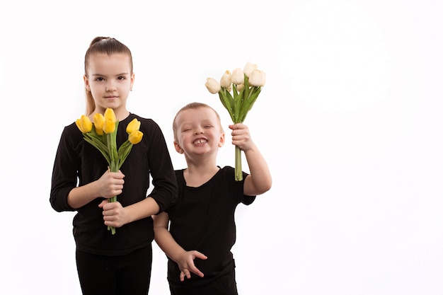 Adolescente niño y niña con ramo de tulipanes. Retrato de feliz hermano y hermana sobre fondo blanco.