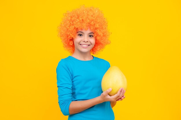 Adolescente niño niña sostenga cítricos pummelo o pomelo lleno de vitamina aislado sobre fondo amarillo Niño alimentación saludable Retrato de adolescente feliz Niña sonriente