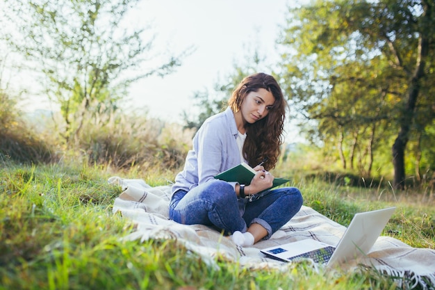 Adolescente nostálgico está sentado en el parque y leyendo un libro