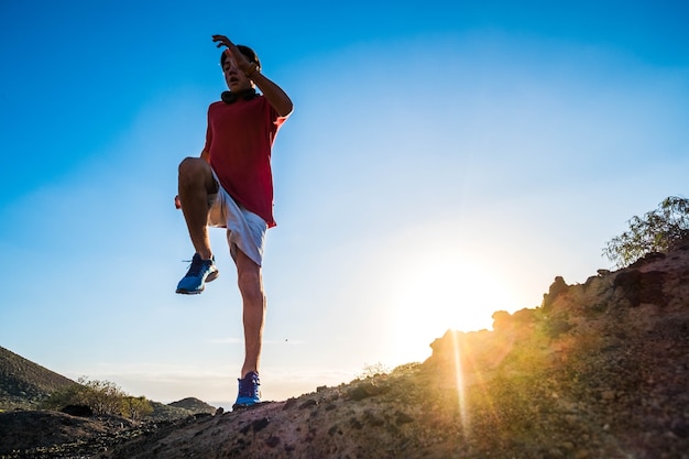 Un adolescente o un adulto corriendo solo al atardecer en las montañas con un hermoso cielo azul de fondo - estilo de vida saludable y fitness