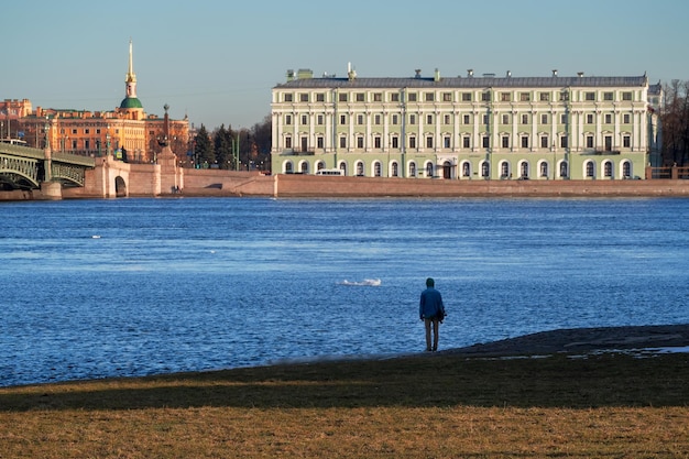 Adolescente olha para o rio azul de Neva em São Petersburgo, Rússia Vista traseira Arquitetura de aterros de rios e canais de São Petersburgo