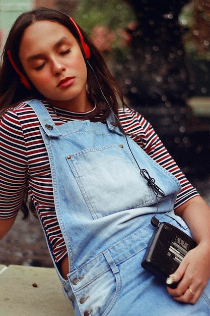 Foto adolescente ouvindo música em fones de ouvido enquanto está sentada ao ar livre