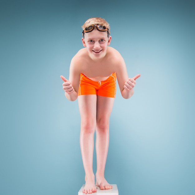 Foto adolescente en pantalones cortos de color naranja y gafas de natación