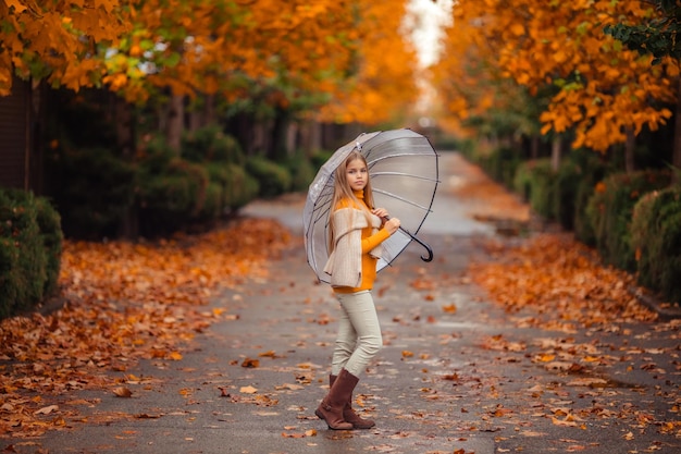 Foto adolescente con un paraguas transparente en sus manos en un paseo en otoño en una calle de la ciudad