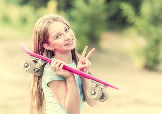 Adolescente con patineta rosa sonriendo