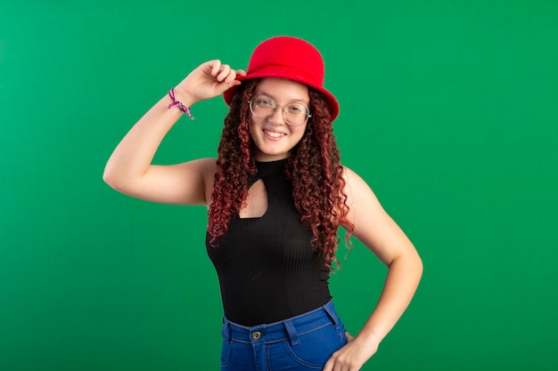 Una adolescente pelirroja con un sombrero rojo en una foto de estudio con un fondo verde ideal para recortar