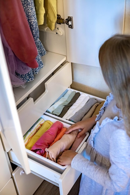 Adolescente con el pelo largo enrollado la ropa utiliza el método marie kondos colocando la ropa en el armario