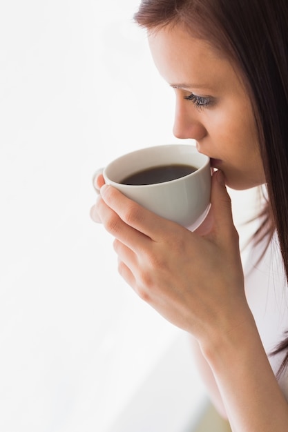 Adolescente pensativo segurando uma xícara de café olhando para longe