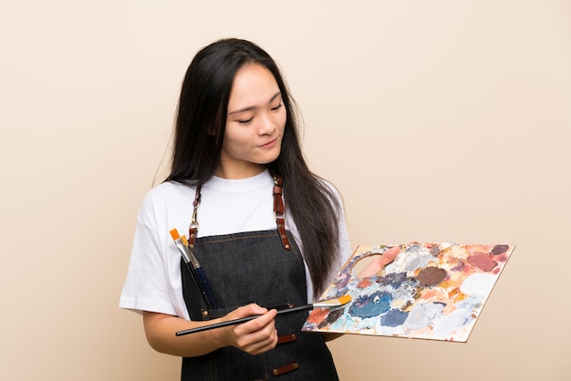 Adolescente pintor chica asiática sobre pared aislada