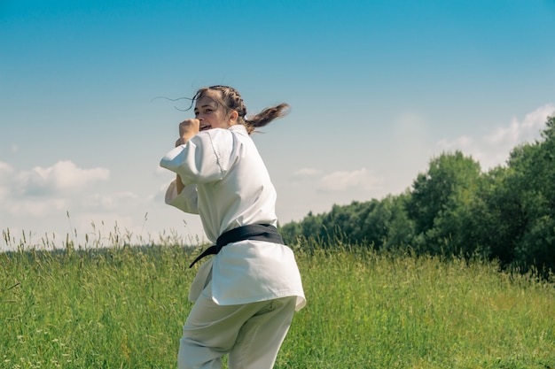 Adolescente practicando karate kata al aire libre, se prepara para uro mawashi geri (patada de gancho)