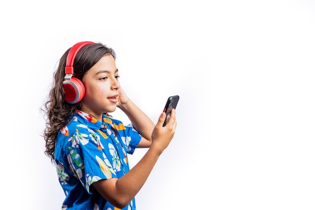 Adolescente prelatino con un teléfono móvil y auriculares sobre fondo blanco.