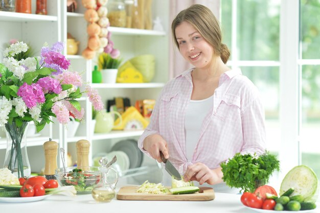 Una adolescente preparando una ensalada fresca.