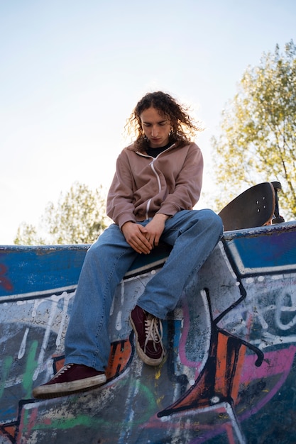 Foto adolescente rebelde no skatepark de baixo ângulo