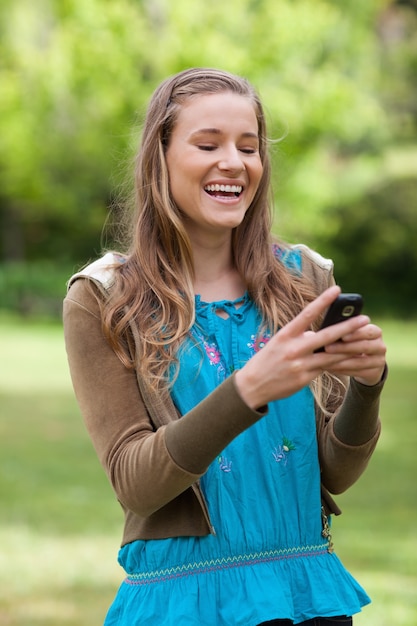 Adolescente rindo enquanto recebe um texto em seu celular