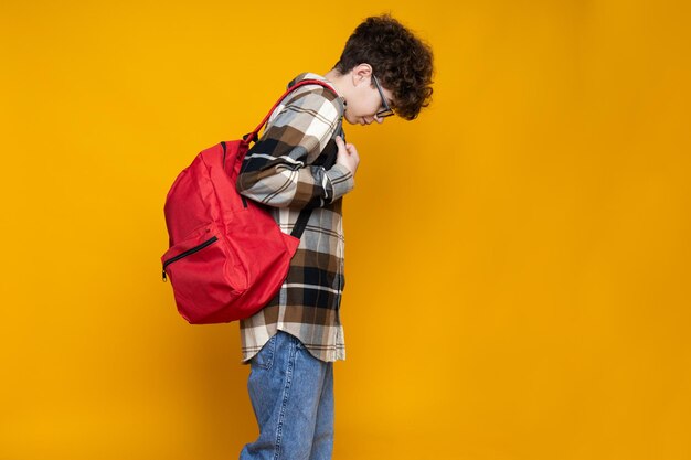 Foto adolescente rizado con un maletín sobre un fondo amarillo