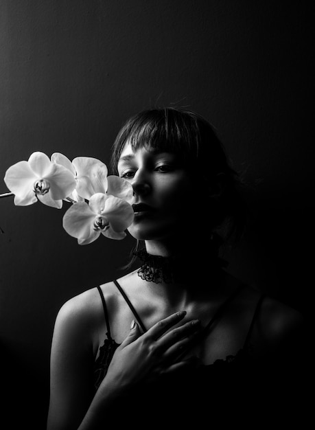 Adolescente romântico com orquídea em preto Retrato de uma jovem adorável em flores Beauty Girl