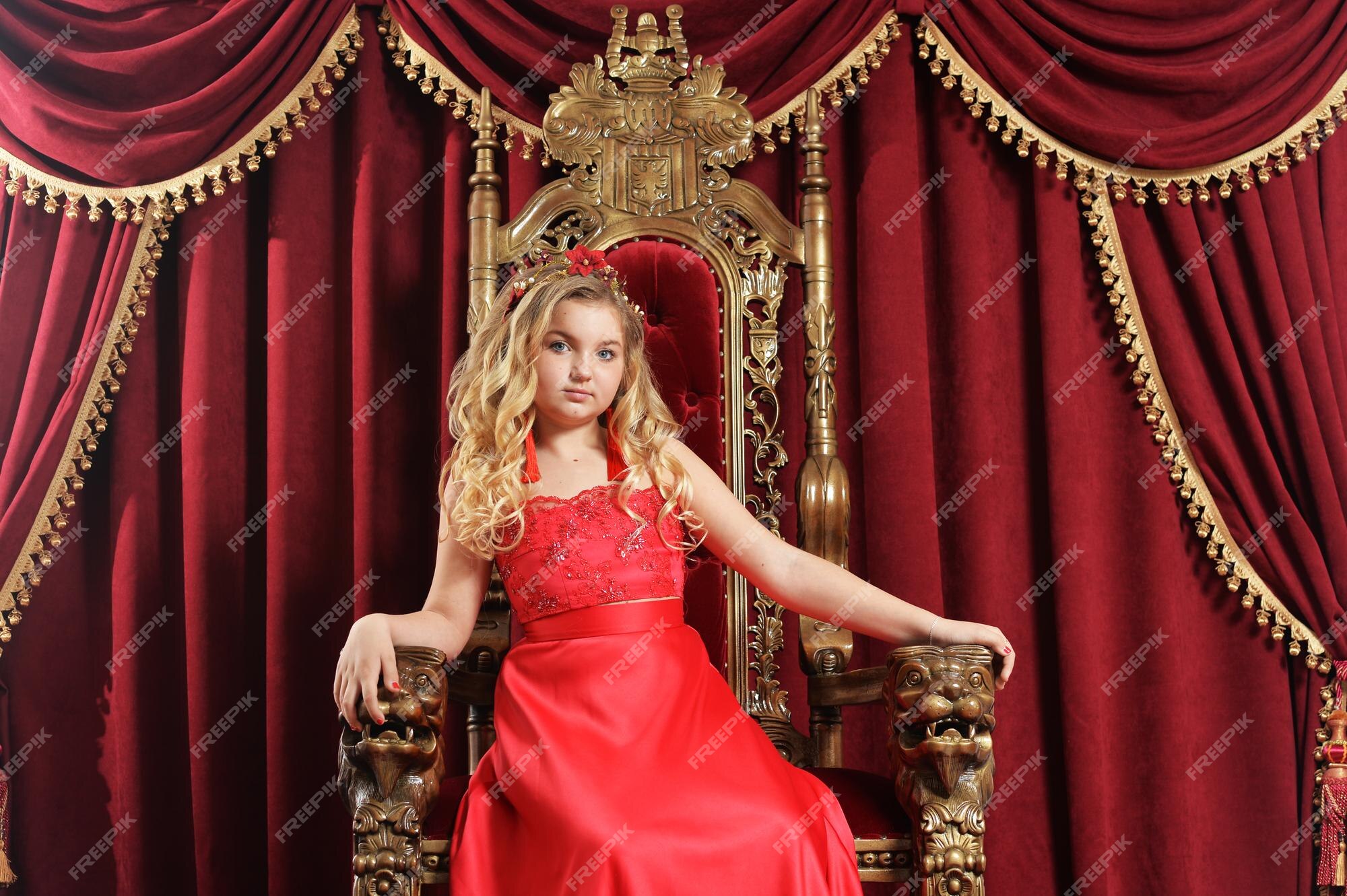 Una adolescente rubia con un vestido rojo brillante sentada en una silla antigua | Premium