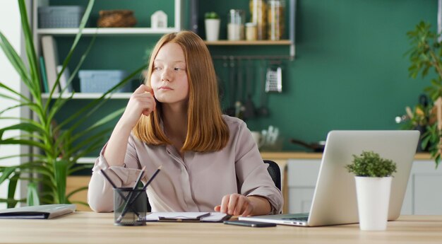 Adolescente ruiva alegre estudando on-line, ensino doméstico confortável on-line