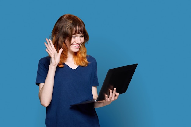 Adolescente ruiva com laptop em fundo azul