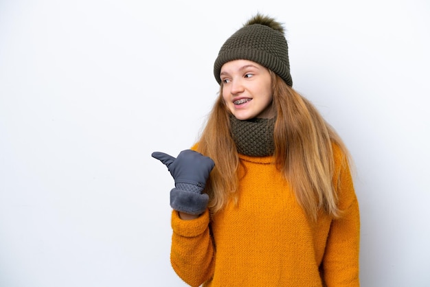 Adolescente rusa con chaqueta de invierno aislada de fondo blanco apuntando hacia un lado para presentar un producto