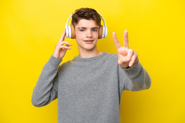 Adolescente ruso aislado de fondo amarillo escuchando música y cantando