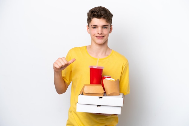 Adolescente ruso hombre sosteniendo comida rápida aislado sobre fondo blanco orgulloso y satisfecho de sí mismo