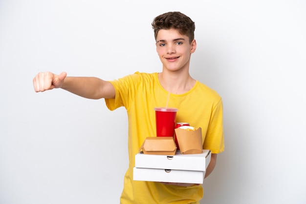 Adolescente ruso hombre sujetando comida rápida aislado sobre fondo blanco dando un gesto de aprobación