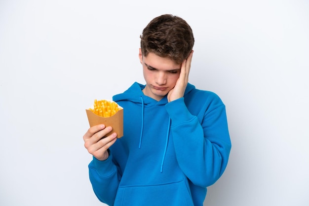 Adolescente ruso hombre sujetando patatas fritas aislado sobre fondo blanco con dolor de cabeza