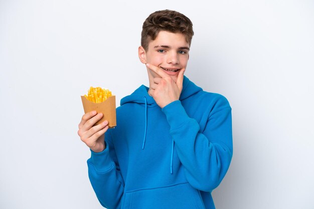 Adolescente ruso hombre sujetando patatas fritas aislado sobre fondo blanco feliz y sonriente